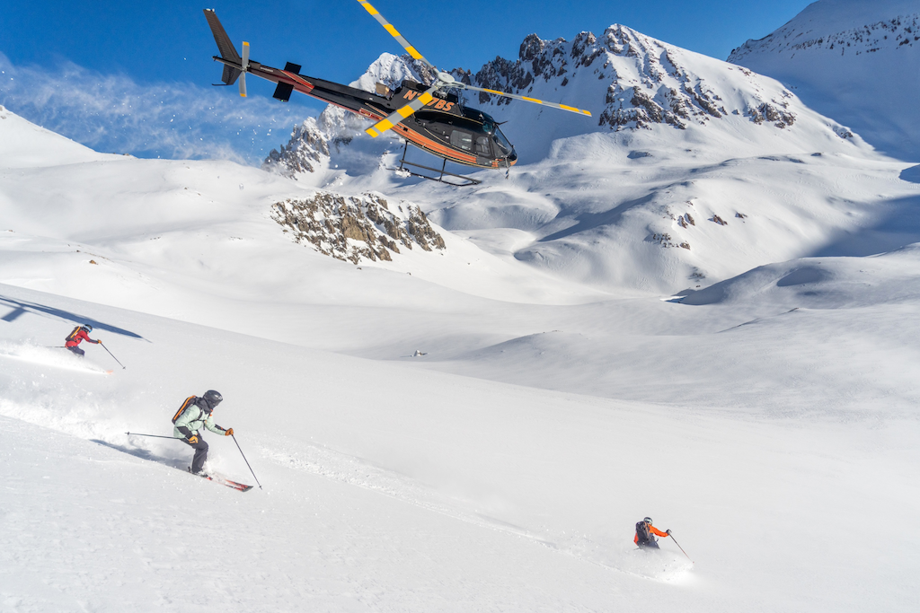 helicopter hovering over skiers 