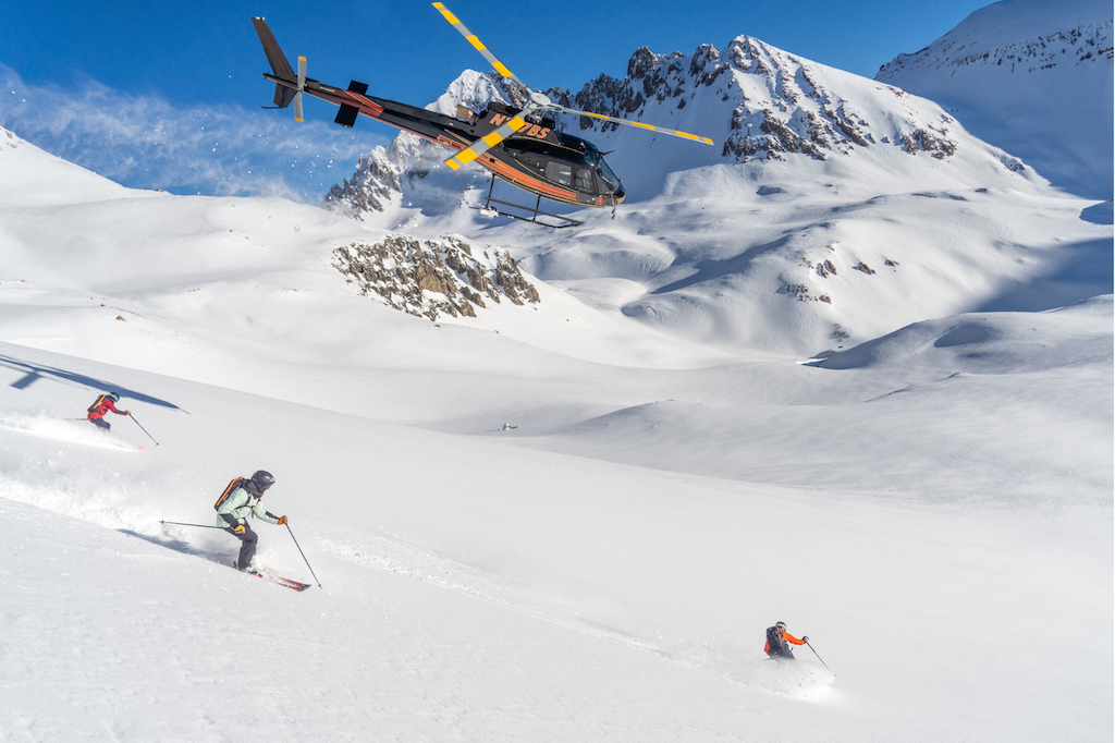 helicopter hovering over skiers