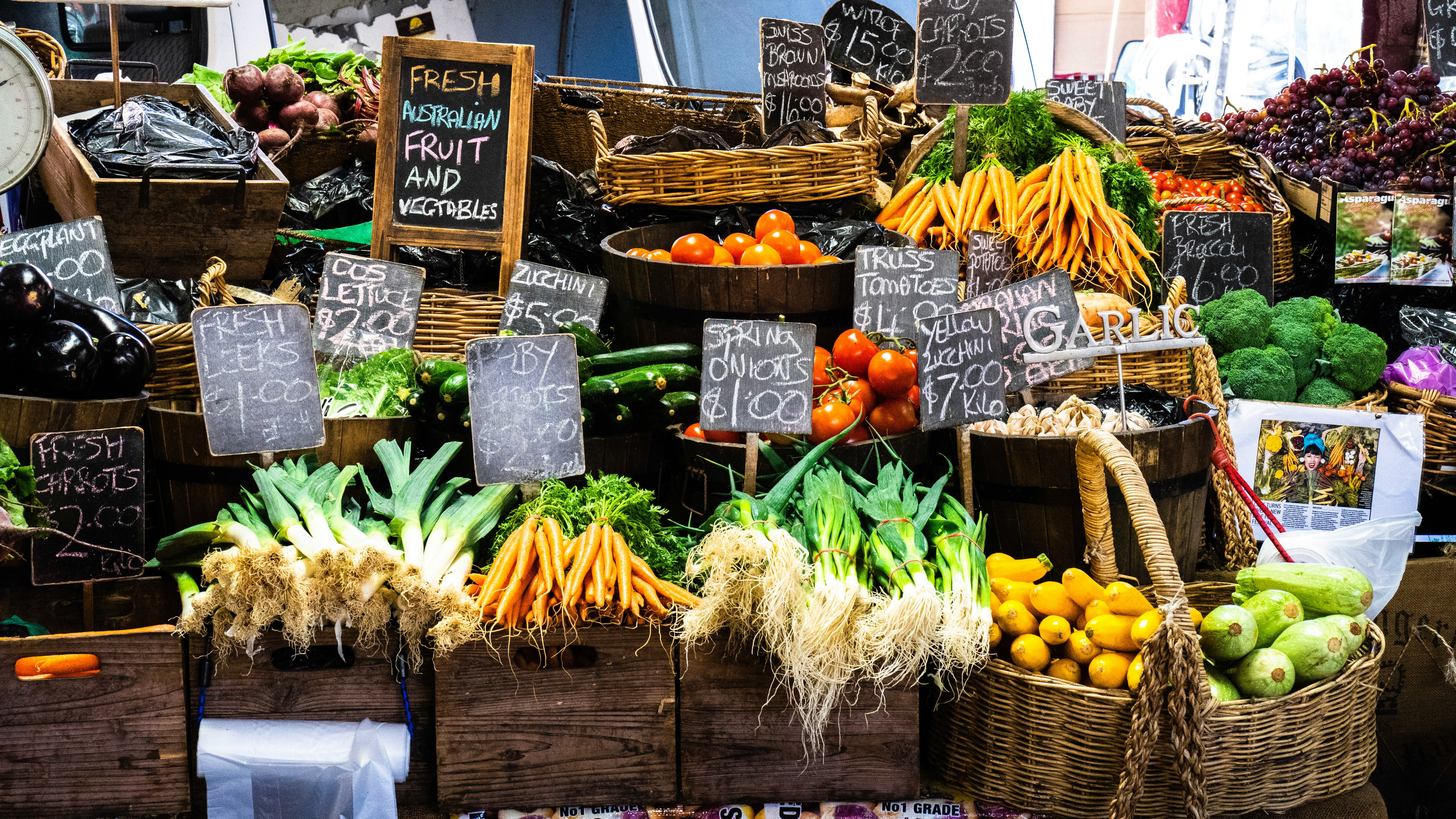 fruits and vegetables in baskets with signs on a farm stand