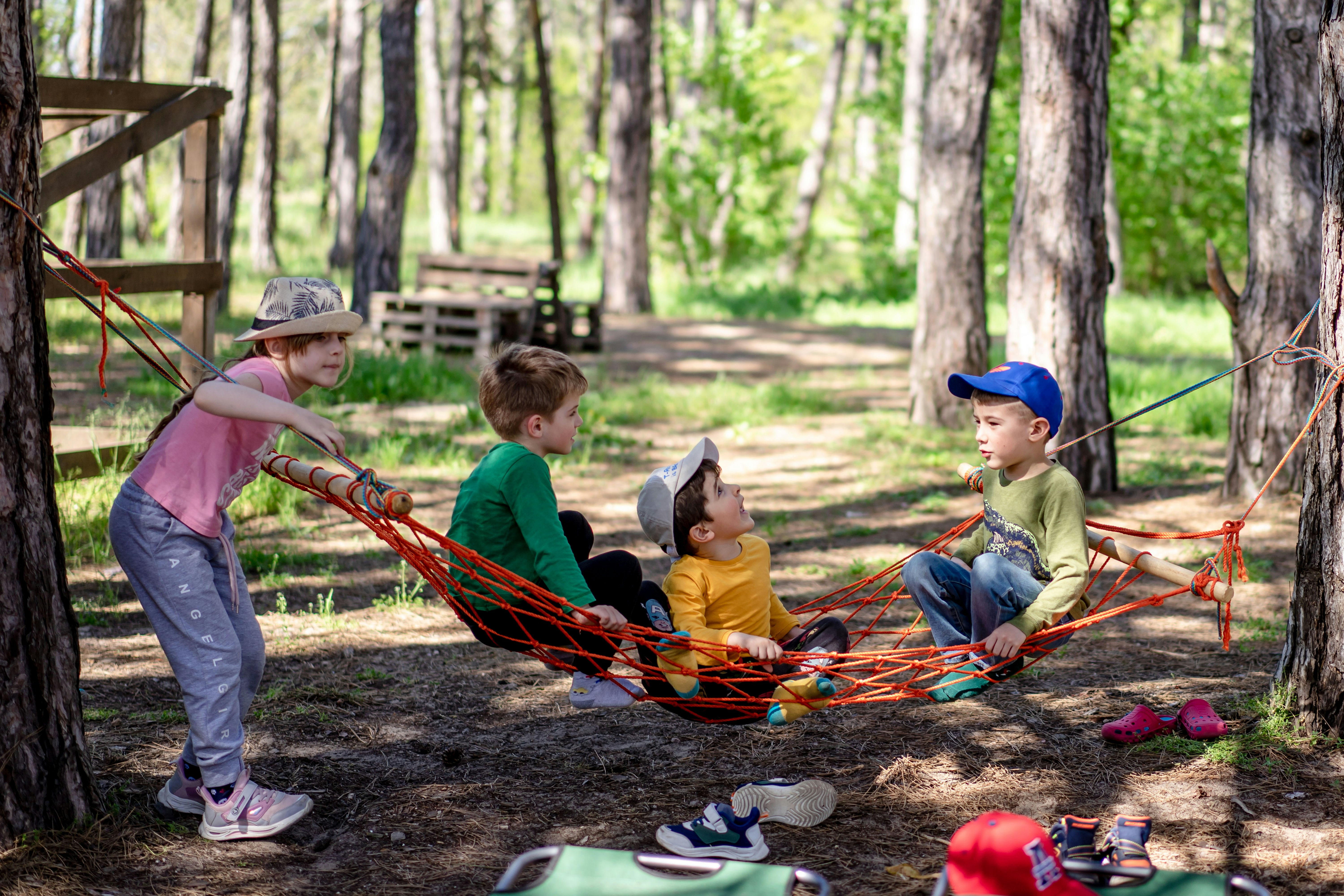 four kids in the woods sitting on a homemade hammock
