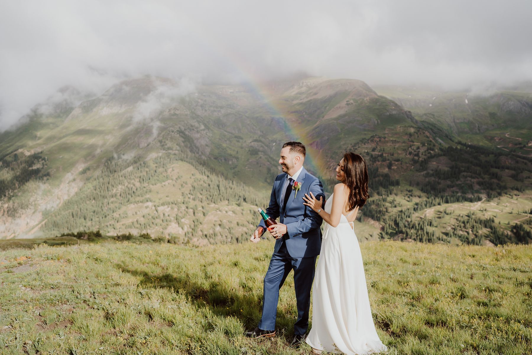 Bride and groom standing in front of rainbow