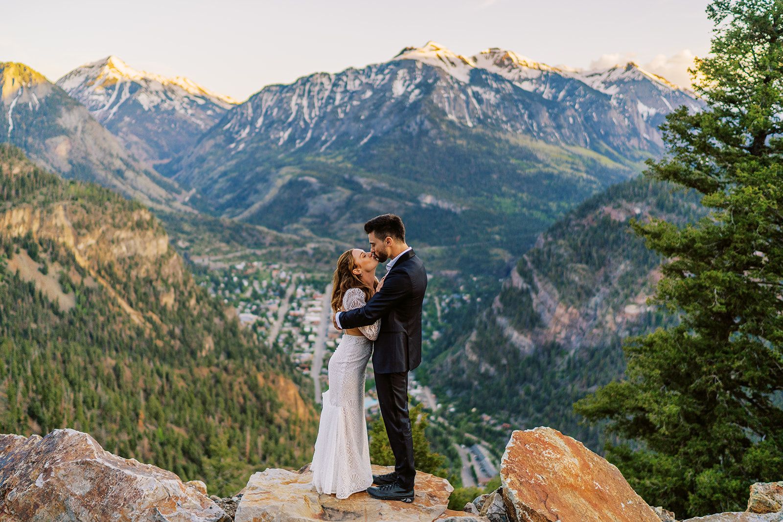 bride and groom kiss looking over a town 